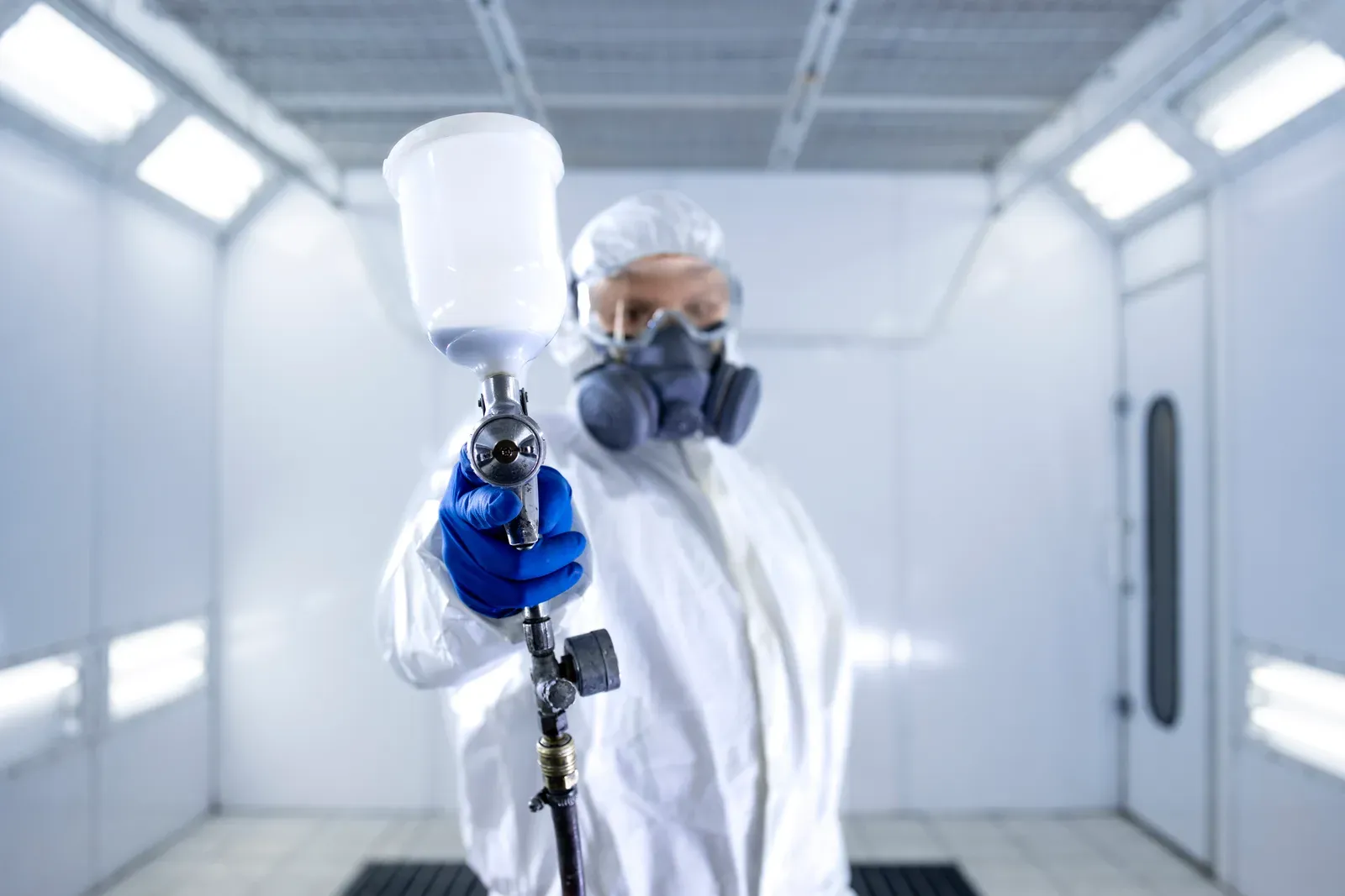 Painter in the booth, spray gun in hand